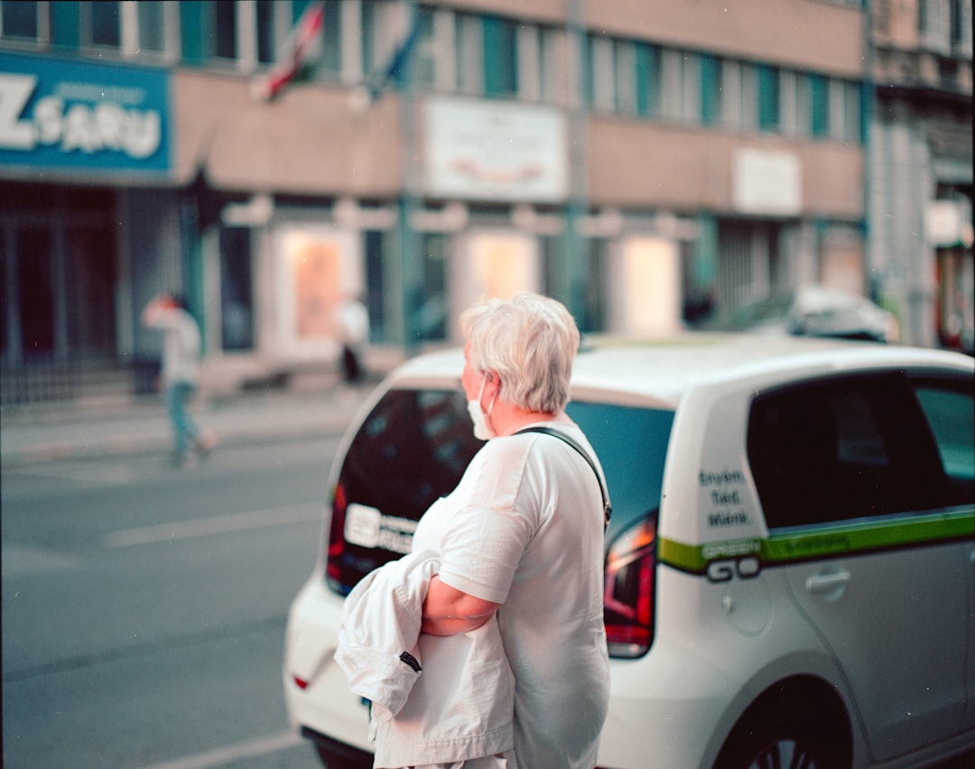 woman in white long sleeve shirt standing beside white car during daytime