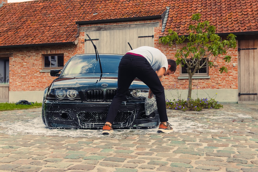 A person washing a black car with soap suds.